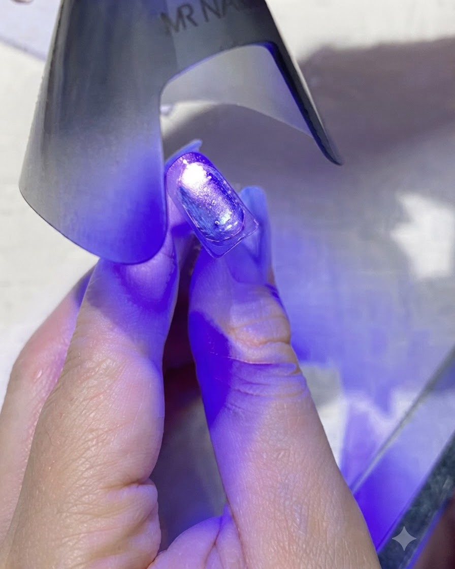 Une mini lampe à ongles UV/LED portable violette émettant une lumière violette directement sur un ongle enduit.