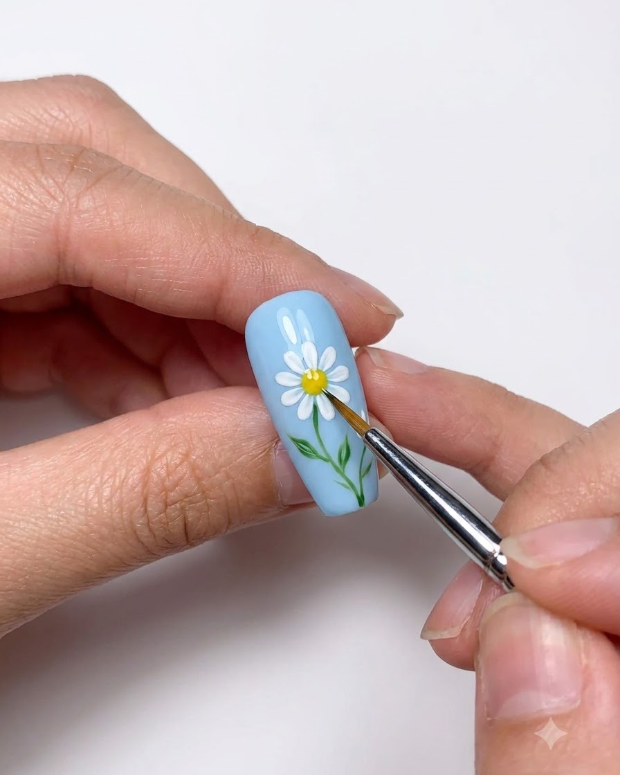 Gros plan dun outil de dotting plaçant un cœur jaune sur la marguerite blanche peinte.
