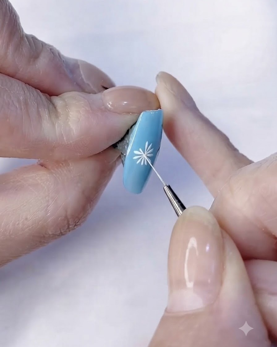 Un pinceau fin finalisant les détails des pétales blancs dun design de nail art marguerite.
