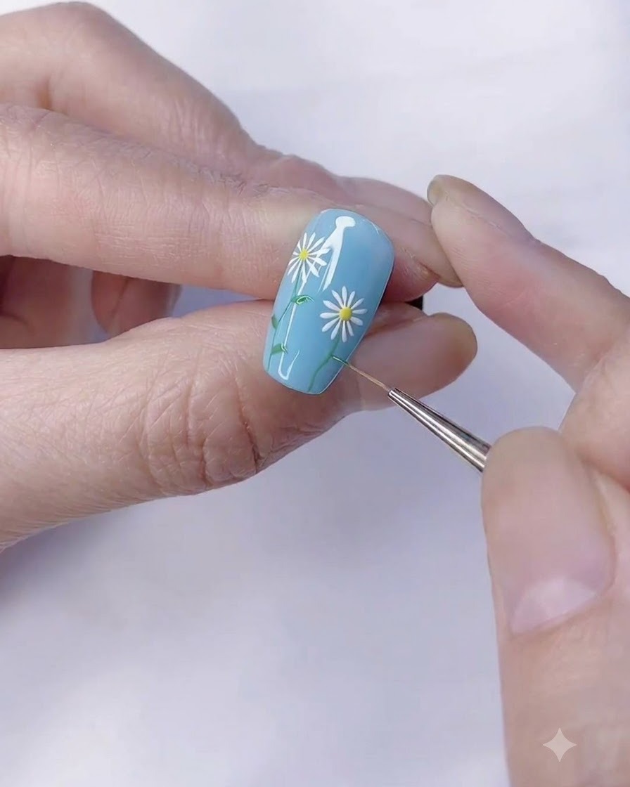 Un pinceau de détail fin ajoutant de petites feuilles vertes à la tige de la marguerite.