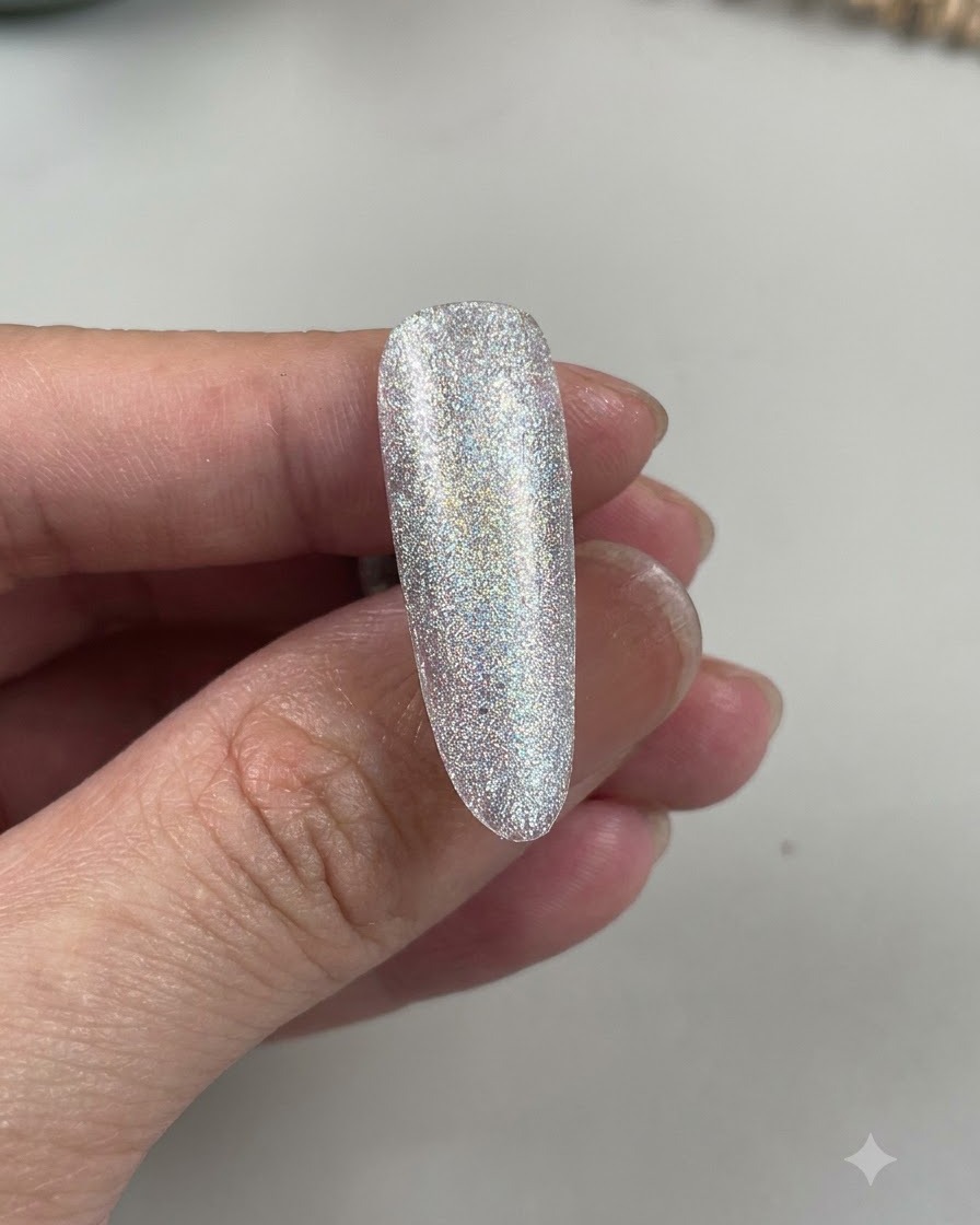 Vue rapprochée dun ongle en amande montrant une teinte bleu clair superposée sur une base scintillante.