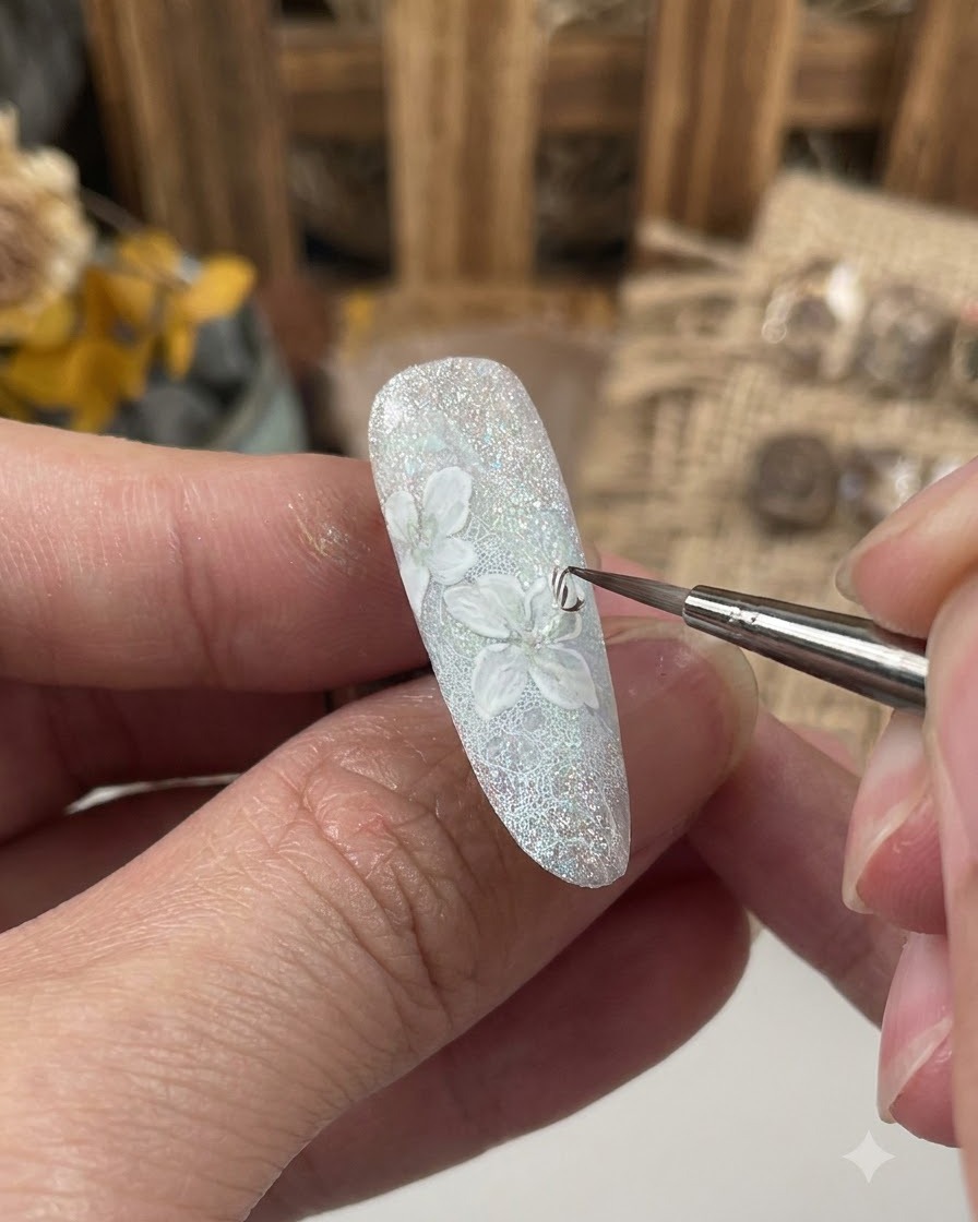 Un pinceau fin appliquant une couche de gel de scellement sur le design floral détaillé dun ongle décoré.