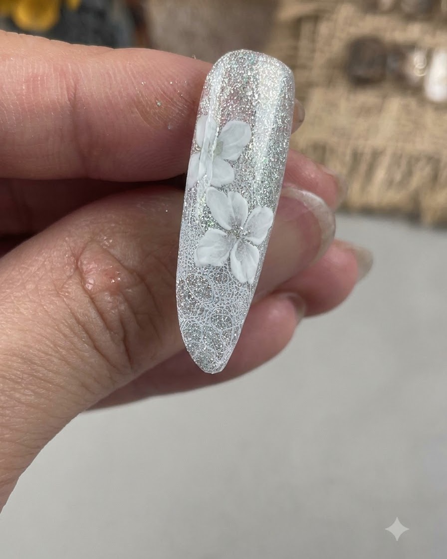 Gros plan dun ongle montrant une deuxième couche de pétales blancs peints en décalé par rapport à la base florale initiale.