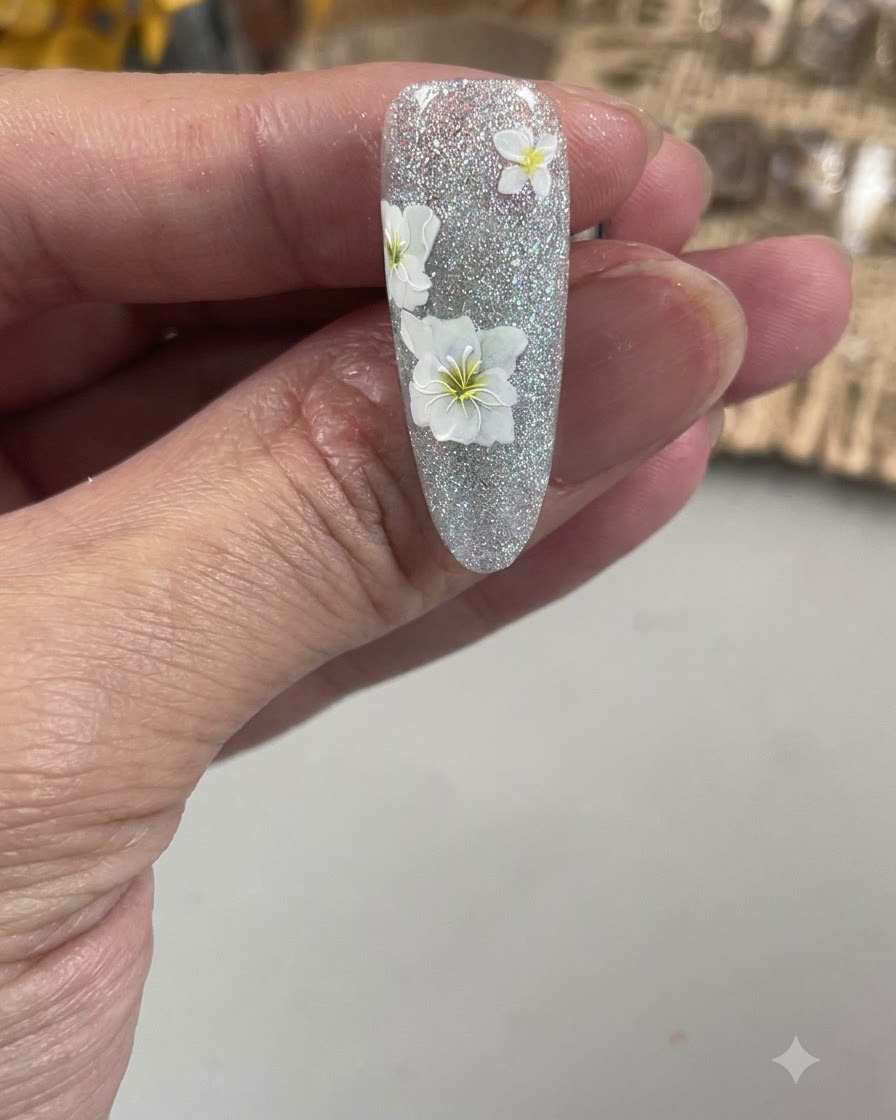 Vue rapprochée dun pinceau de nail art fin dessinant le contour des délicats pétales dune fleur blanche sur un ongle texturé.