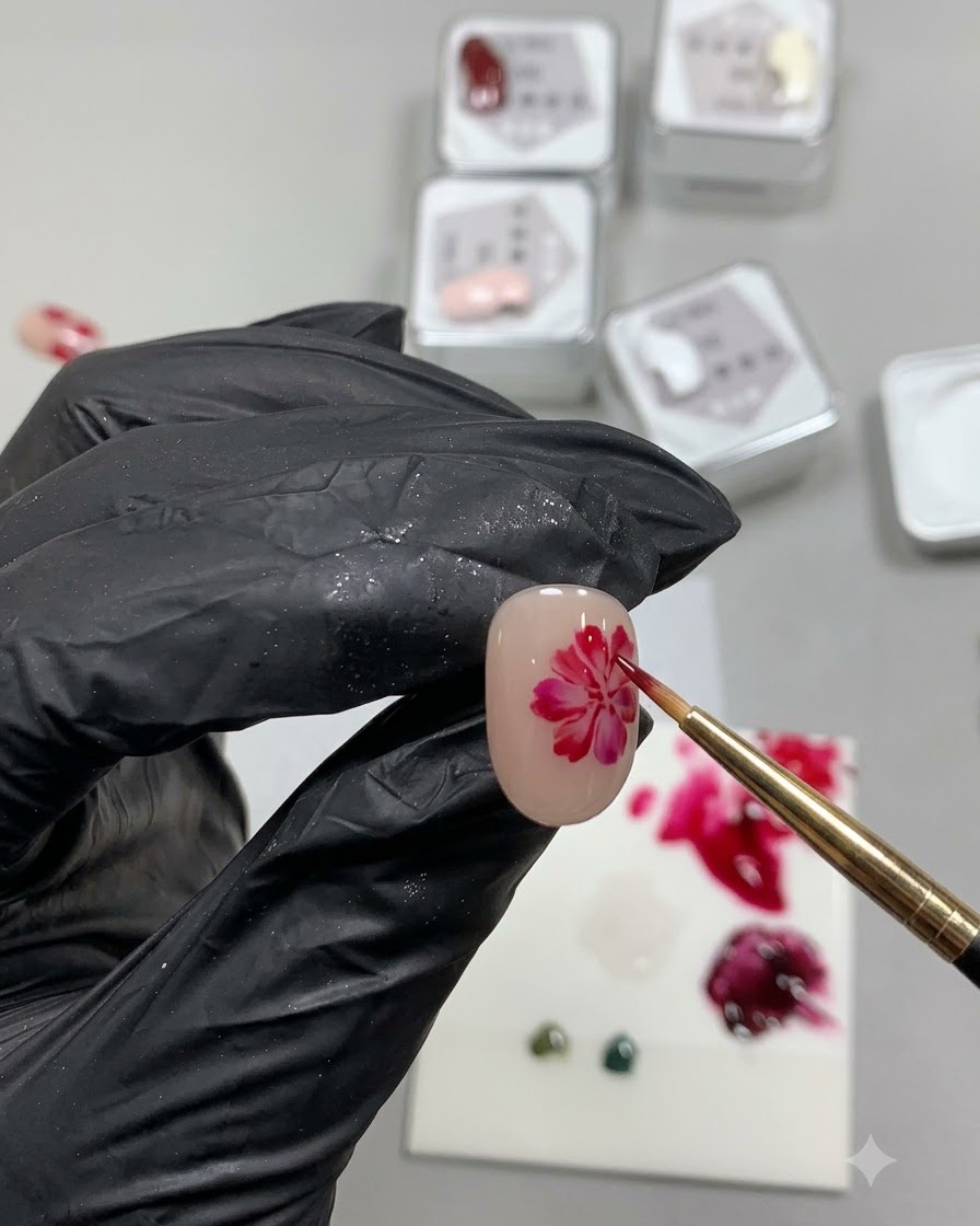 Un pinceau de détail fin peignant un cercle rouge irrégulier et doux, ressemblant à une base de pétale de rose sur un ongle nude.