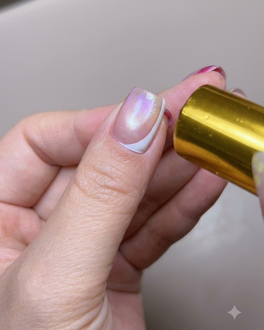 Un ongle de pouce doté dune ligne French latérale blanche catalysée exposé à une lumière de polymérisation.