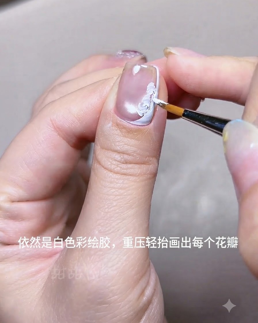 Vue rapprochée dune main utilisant un pinceau liner fin pour peindre des pétales de fleurs en gel acrylique blanc sur un ongle près dune ligne de French blanche.