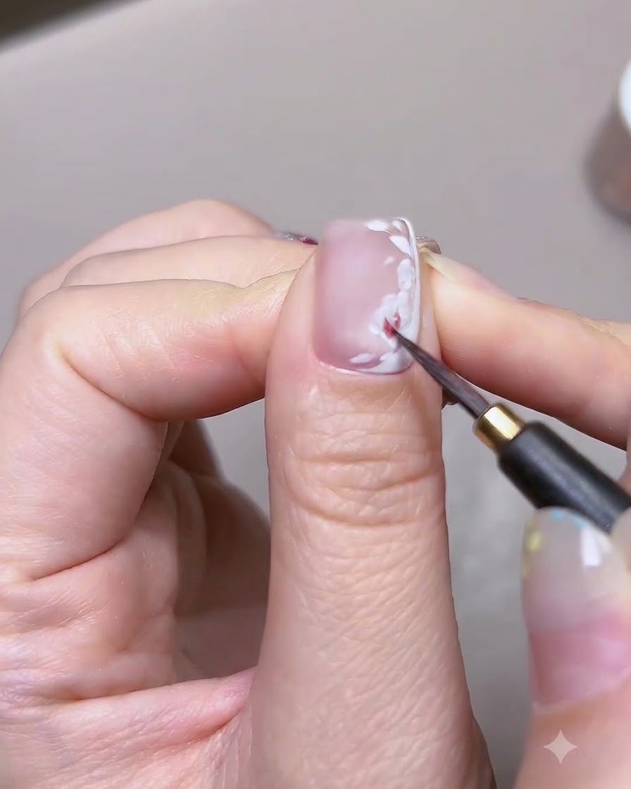 Gros plan détaillé dun pinceau fin appliquant de la peinture aquarelle rouge sur la base de pétales blancs dune rose en nail art.