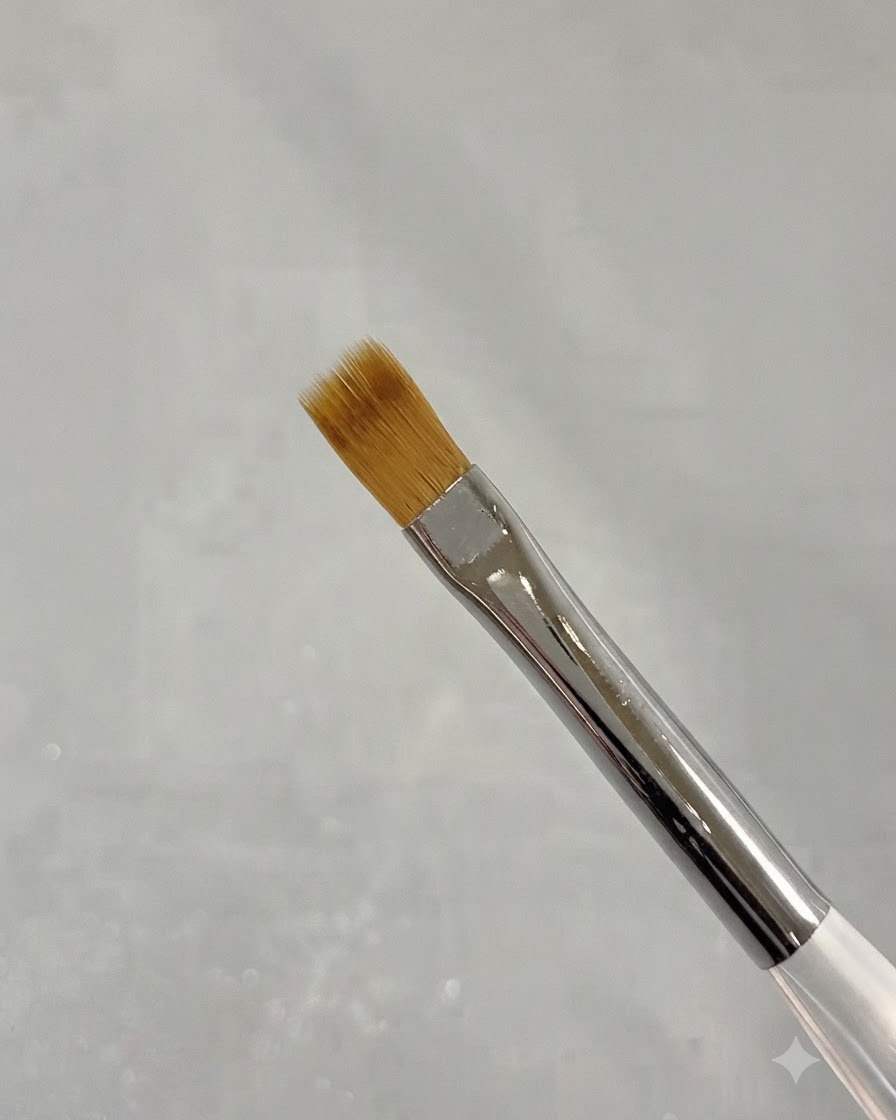 Gros plan dun pinceau balayeur fin pour nail art avec des poils souples marron.