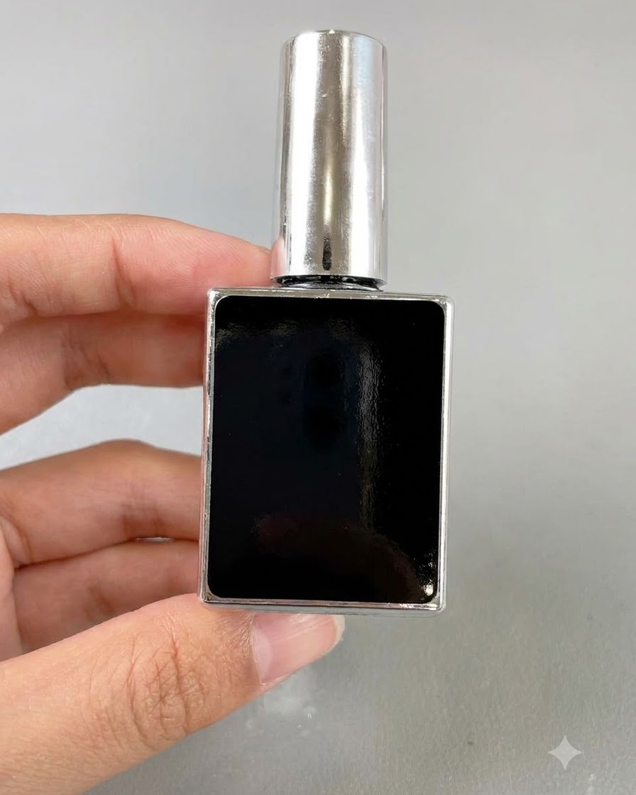 Un petit flacon rectangulaire noir de gel pour ongles tenu par une main sur un fond neutre.