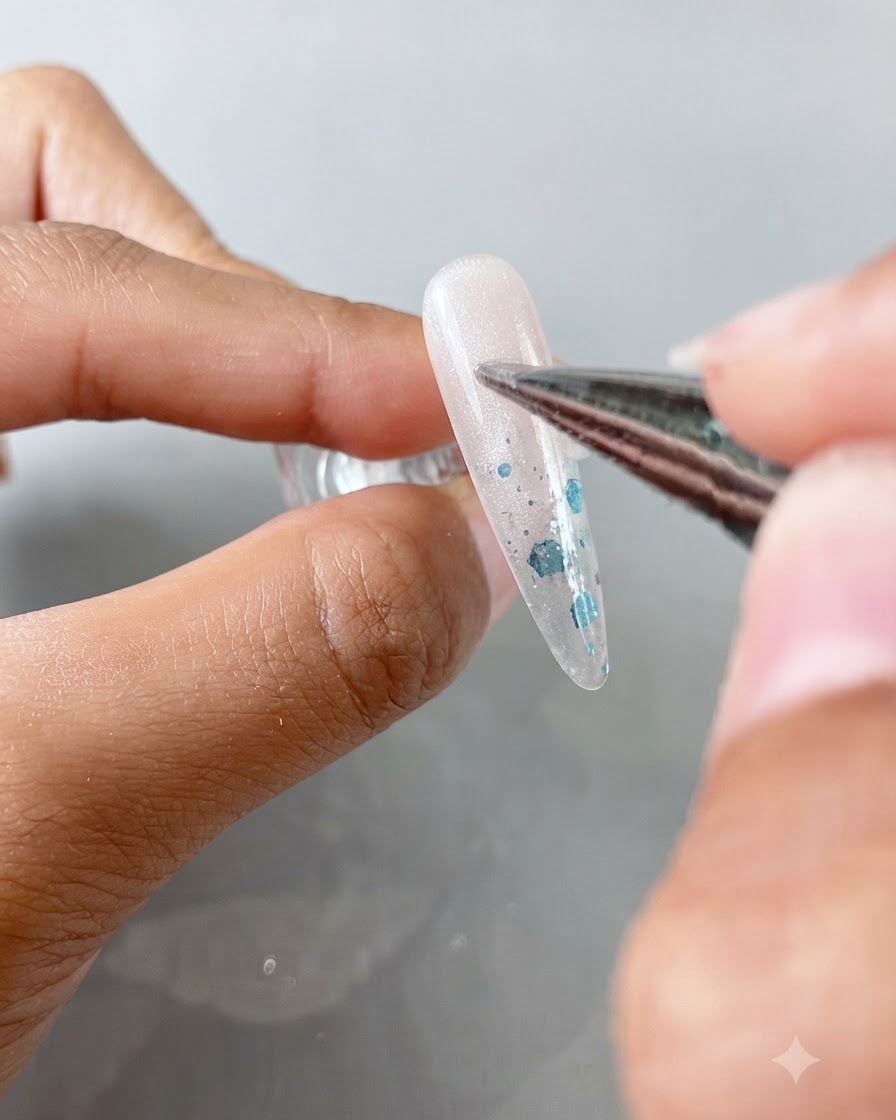 Un pinceau de précision appliquant du gel cat-eye transparent sur un ongle en forme damande.