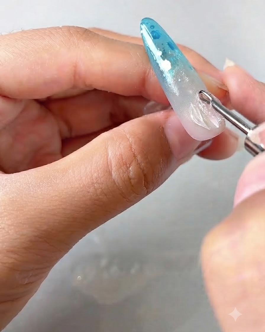 Un outil de détail plaçant et soulevant les bords dun gel de pétale transparent sur un ongle décoré.