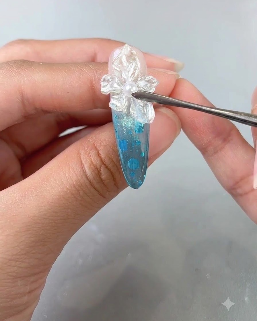 Gros plan dun doigt manucuré recevant une application finale de top coat transparent sur un design dongle à fleurs texturé.