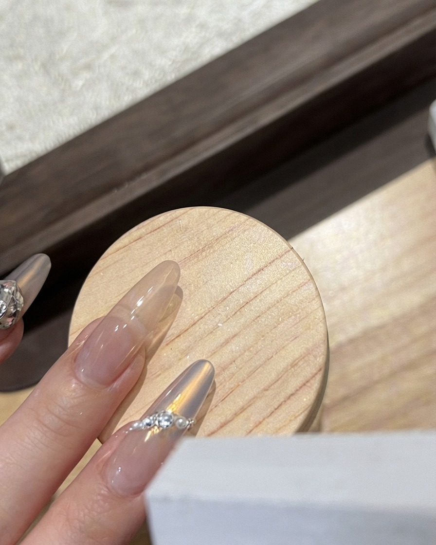 Une prothésiste ongulaire posant un charm papillon blanc givré sur un ongle brillant.
