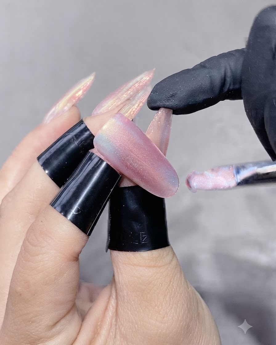 Un pinceau à ongles appliquant un gel œil-de-chat scintillant sur un ongle étendu.