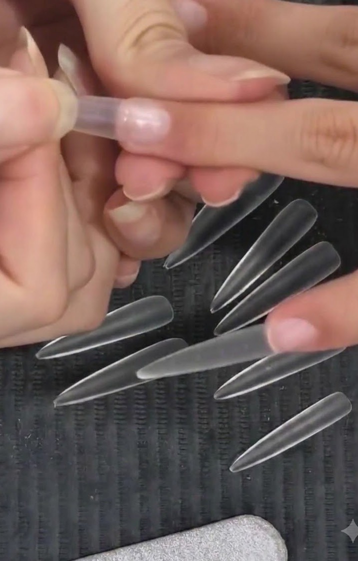 Technicienne appliquant une capsule dongle en amande transparente sur un doigt naturel en utilisant une technique de pose en position haute.