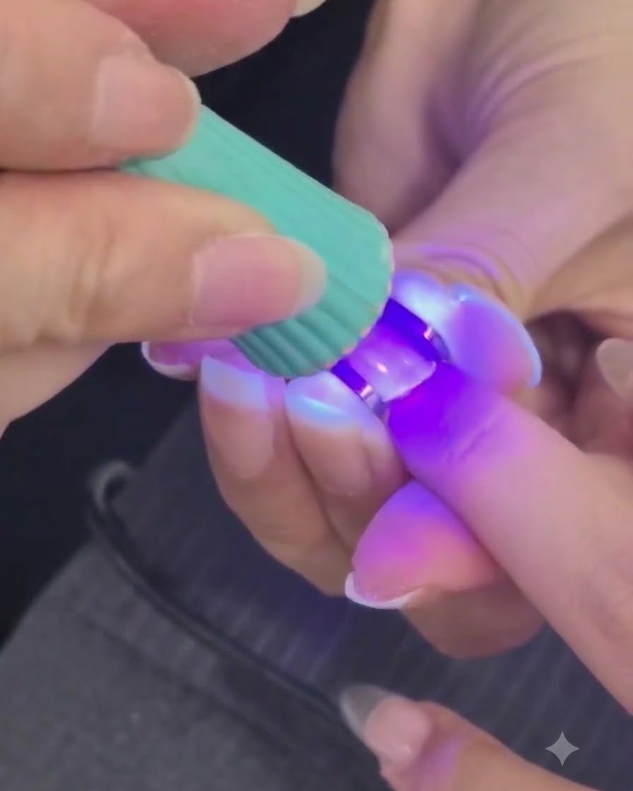Mini lampe UV ou LED catalysant une couche de gel dongle structuré sur un doigt.