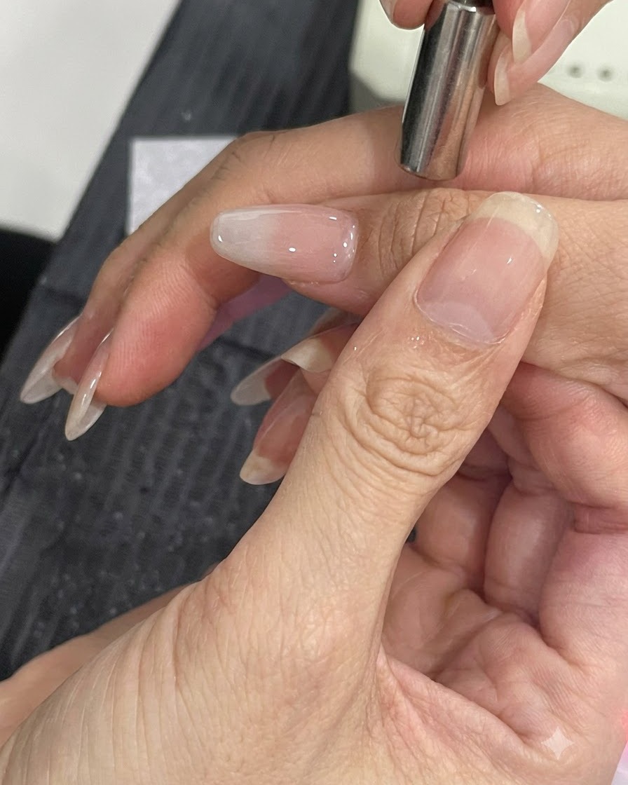 Petit outil magnétique tenu près du côté dun ongle manucuré pour déplacer les particules scintillantes œil-de-chat.
