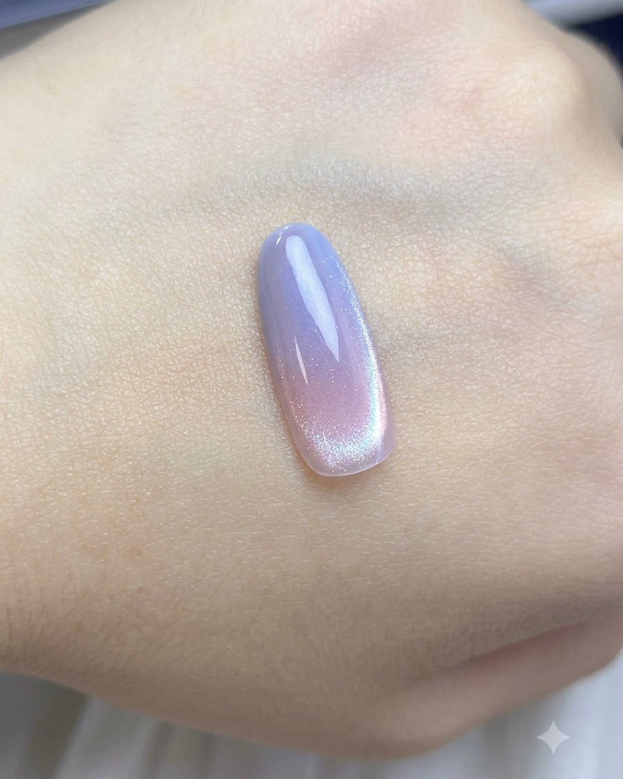 Un pinceau appliquant une couche de vernis cat-eye nude diaphane sur la capsule dongle dégradée.