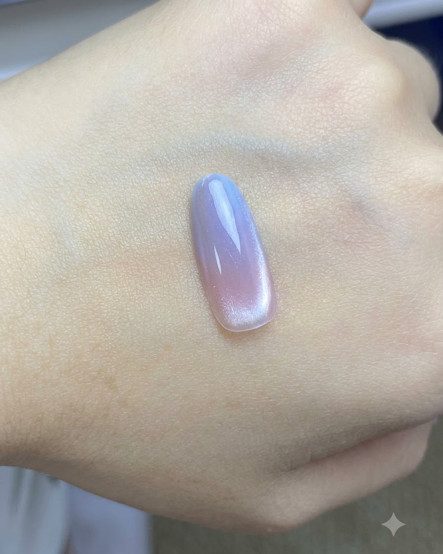 Un pinceau appliquant un top coat brillant final sur le design dongle cat-eye rose et bleu terminé.