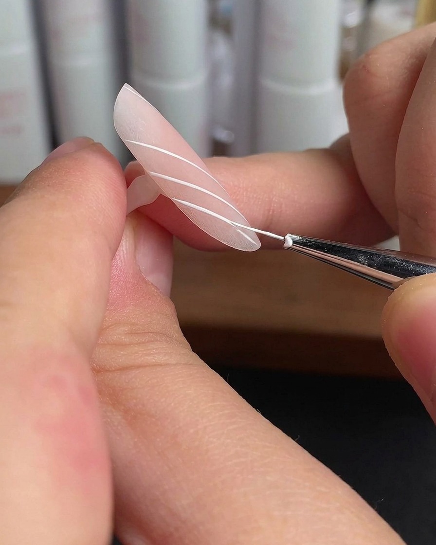 Un ongle dannulaire avec des lignes blanches parallèles en train de catalyser sous la lumière dune lampe.