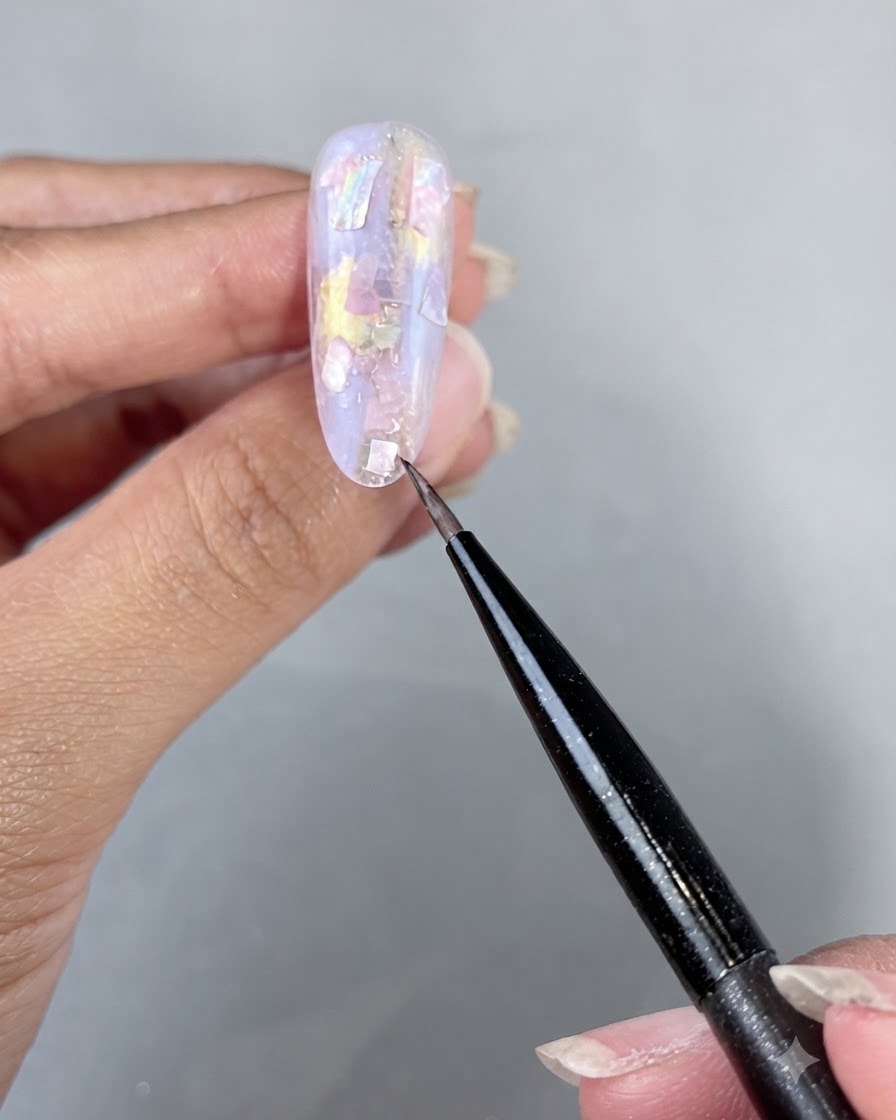 Une main placée sous une lampe à ongles UV LED pour catalyser les morceaux de coquillage et le gel de construction appliqués.