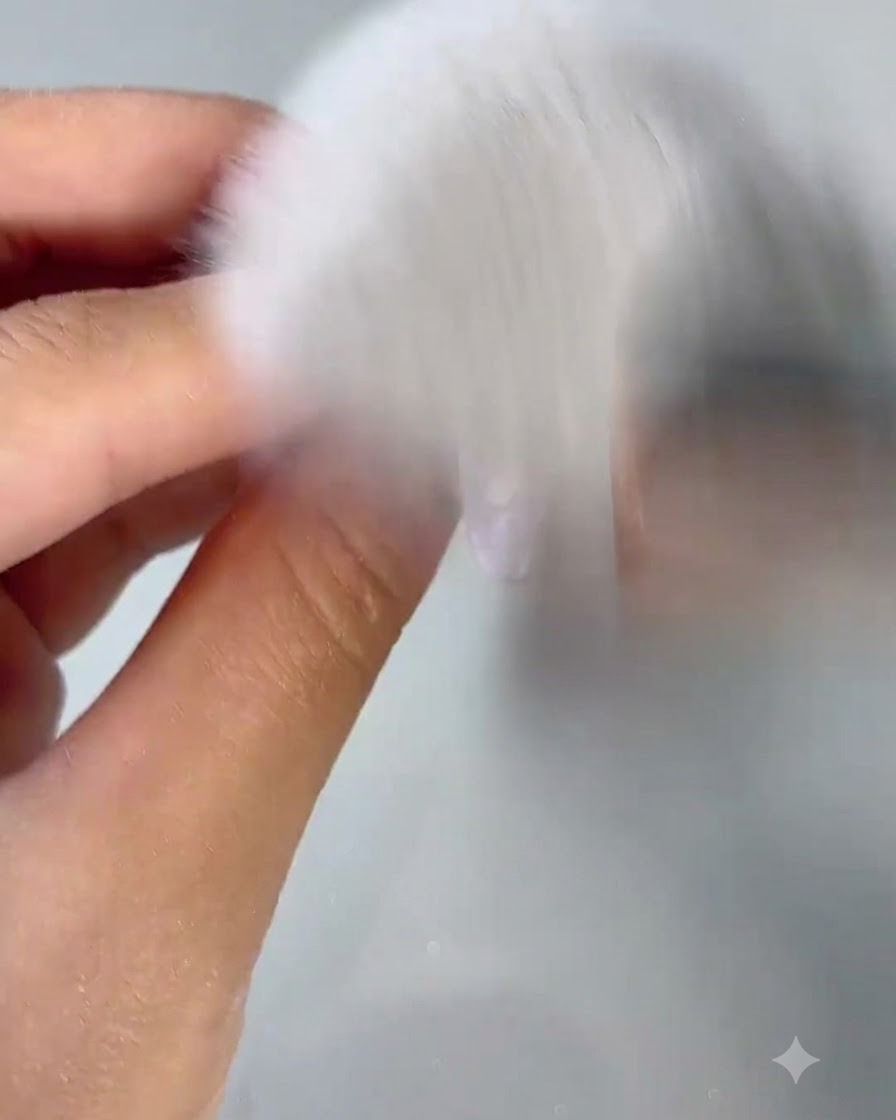 Un pinceau à poussière blanc et touffu balayant la poussière dongle dun ongle fraîchement poli.