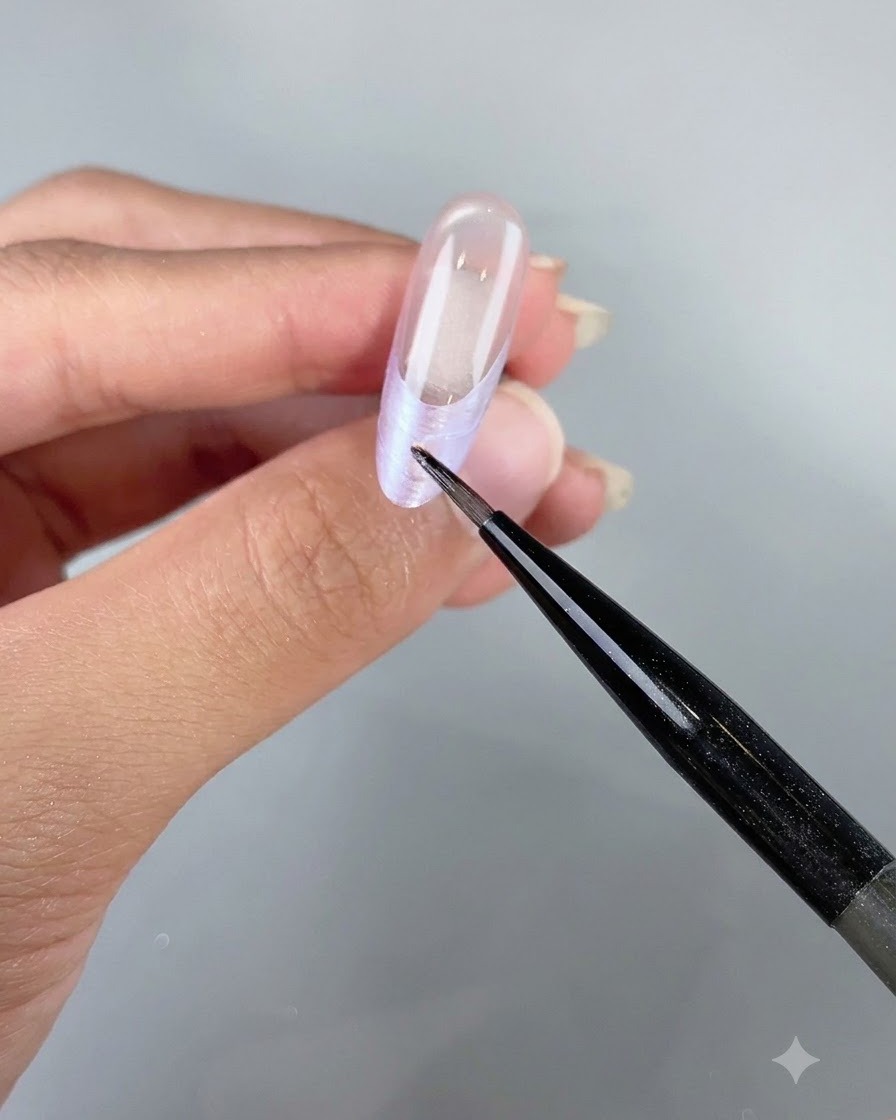 Un outil de précision posant de petits flocons de coquillages irisés le long de la French dun ongle.