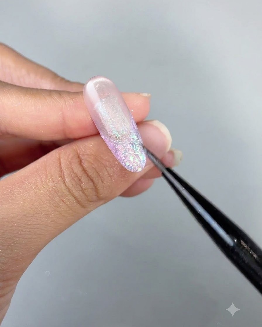 Gros plan détaillé dun pinceau retouchant les détails du gel œil-de-chat sur un design dongle long et brillant.