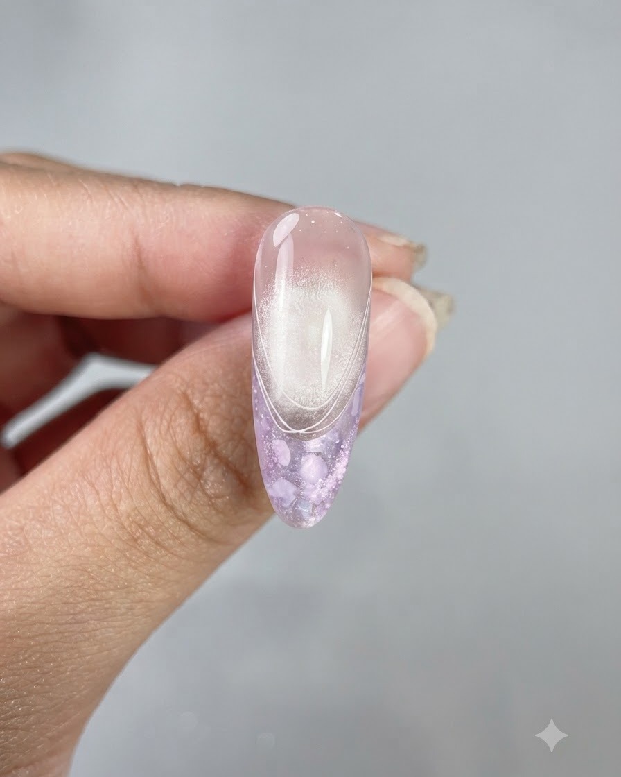 Un ongle long en forme damande mettant en valeur un top coat brillant, un fini œil-de-chat et de délicates lignes de French blanches.