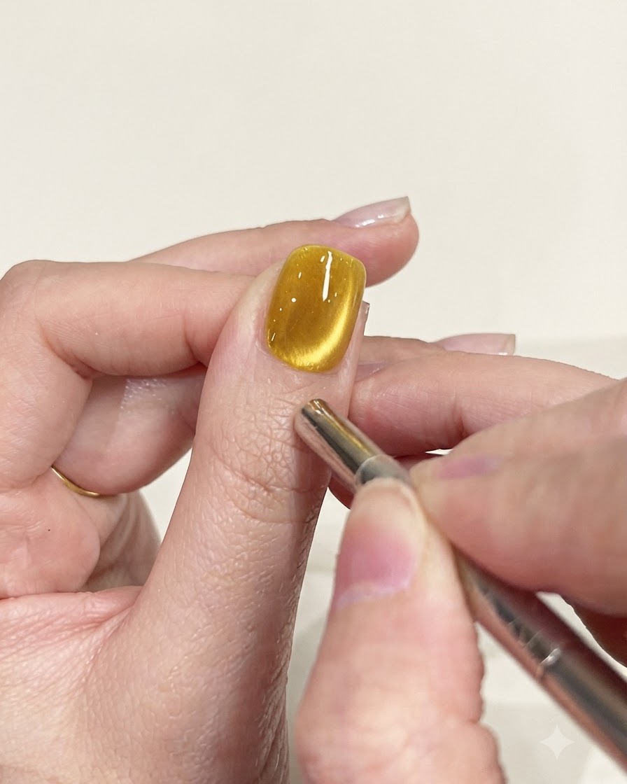 Un stylo aimant de précision utilisé pour affiner le chemin des scintillements sur un ongle œil-de-chat jaune.