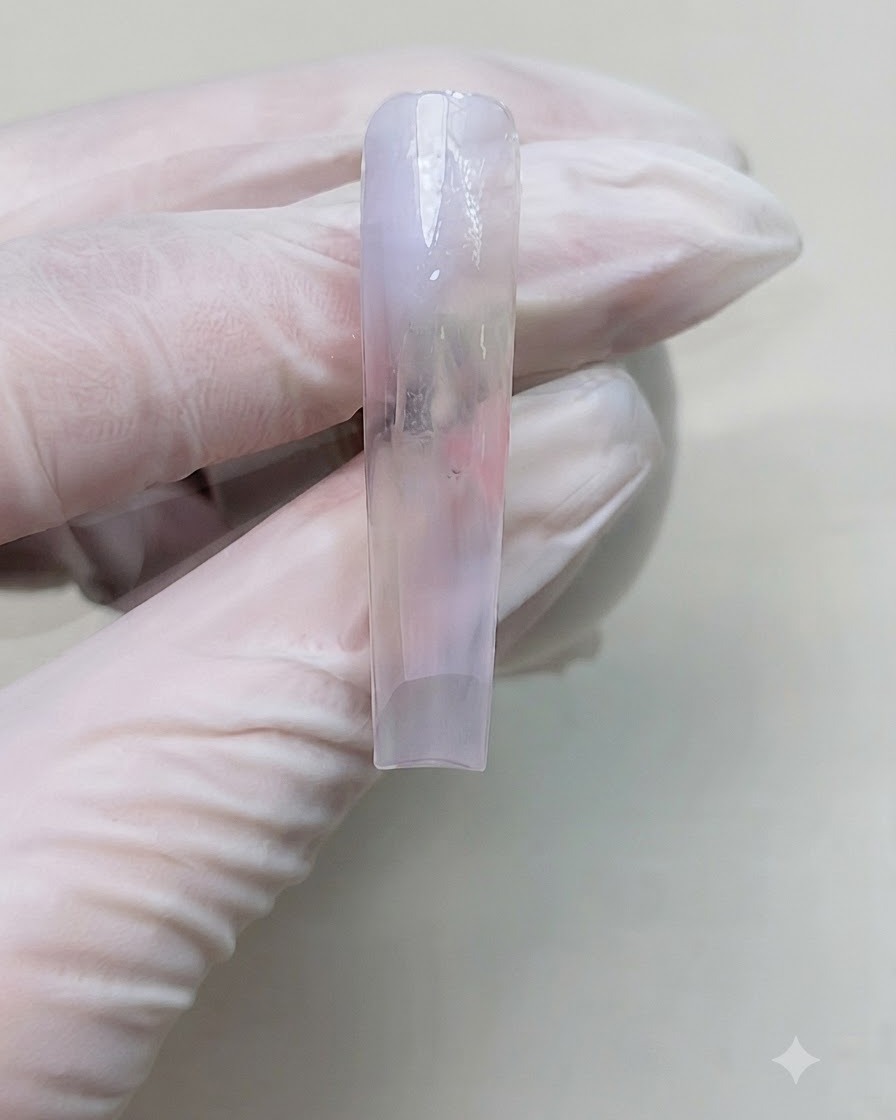 Vue rapprochée dun ongle manucuré après la catalysation de la couche de couleur dégradée sous une lampe à ongles portable.