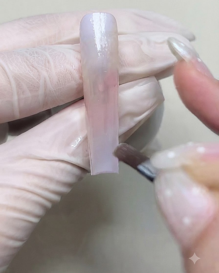 Un pinceau appliquant une seconde couche de gel de couleur pour accentuer la transition du dégradé sur longle.