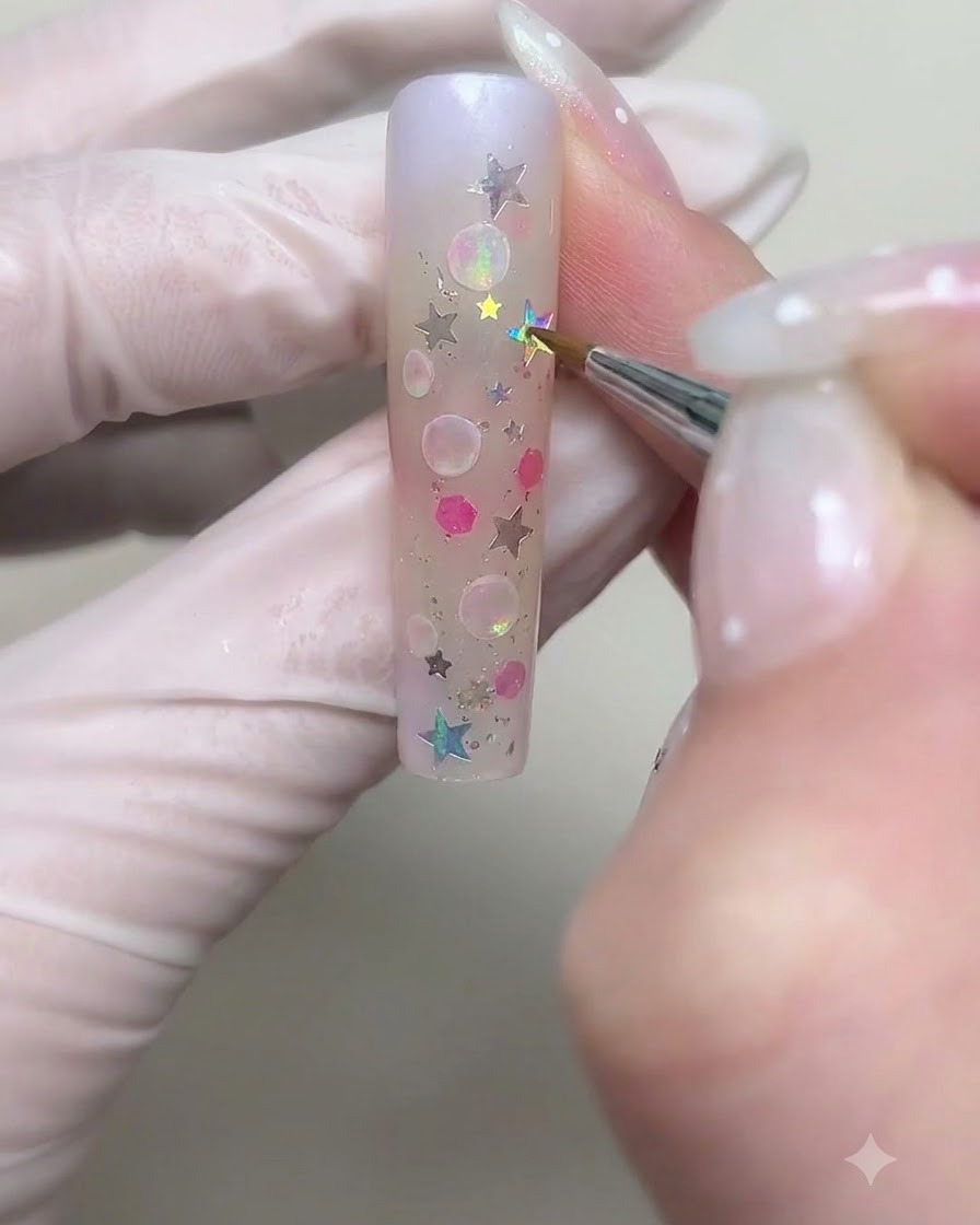 Un pinceau fin dessinant des contours de bulles circulaires plus grands avec du gel crème blanc sur longle.