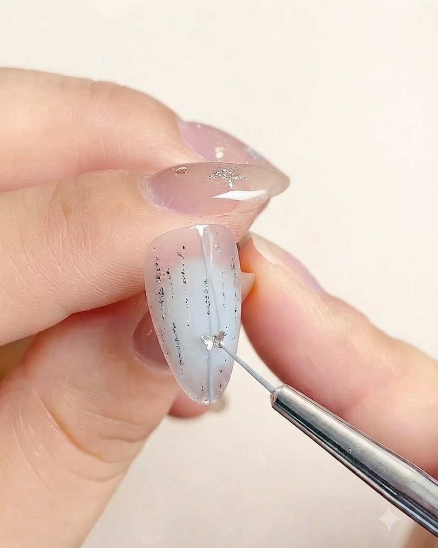 Un outil de précision posant un petit sticker en étoile le long de la ligne centrale dun ongle décoré.