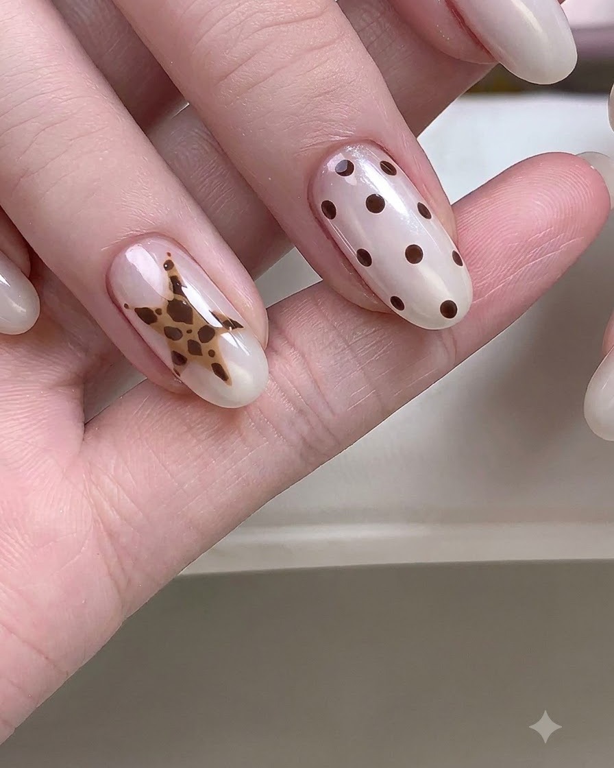 Une main en gros plan montrant des ongles ornés de motifs détaillés détoiles et de pois.