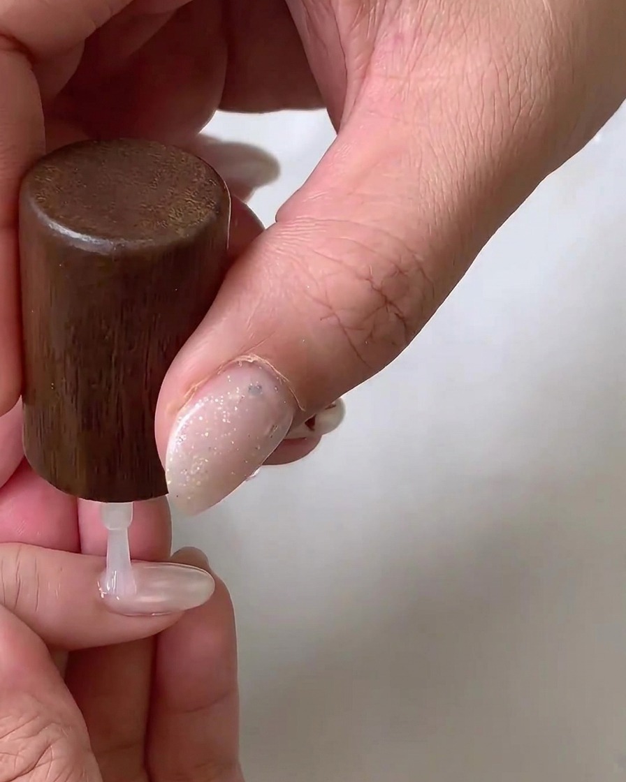 Une ponceuse avec un embout céramique en forme de flamme affinant avec précaution le contour des cuticules dun ongle naturel.