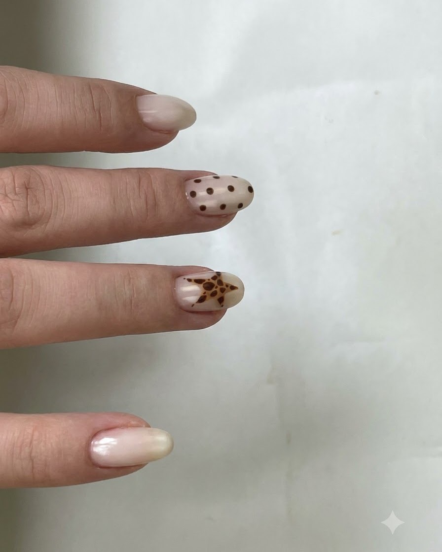 Un pinceau appliquant un top coat transparent sur un ongle arborant des pois marron et une étoile.
