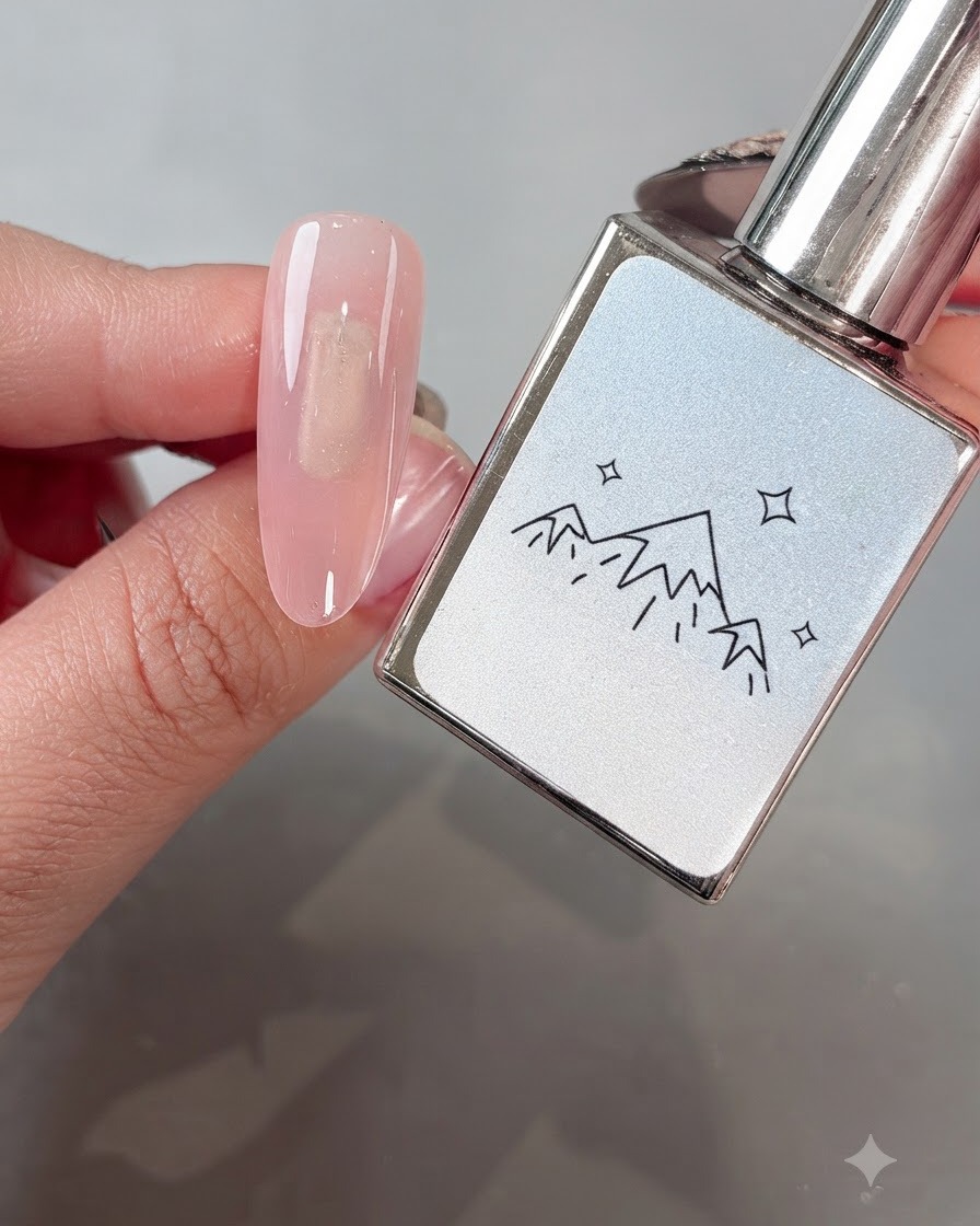 Un pinceau appliquant uniformément le gel œil-de-chat White Boiling Water No. 2 sur un ongle à base rose.