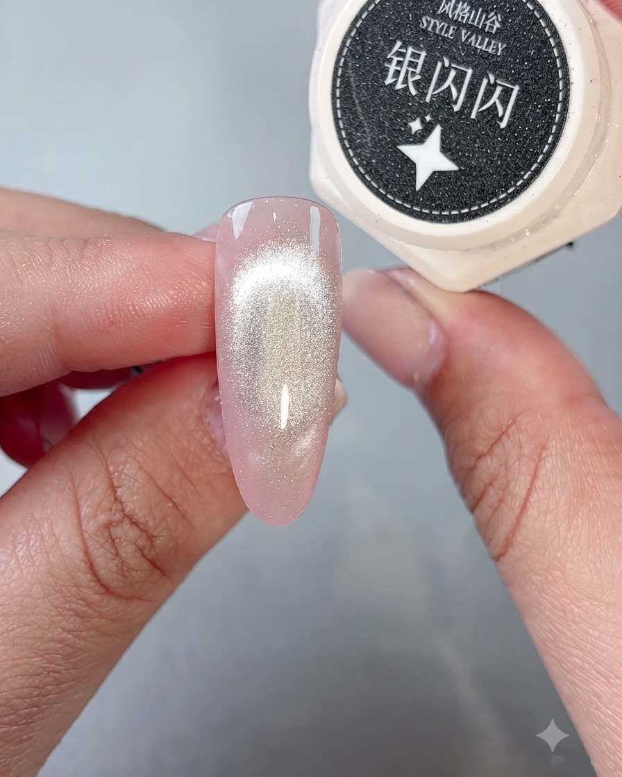 Un pinceau déposant du gel à paillettes argentées étincelantes sur le bout dun ongle fini avec leffet œil-de-chat.