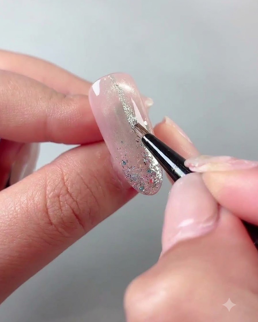 Un pinceau fin trace de fines lignes de paillettes argentées sur la surface dun ongle catalysé.