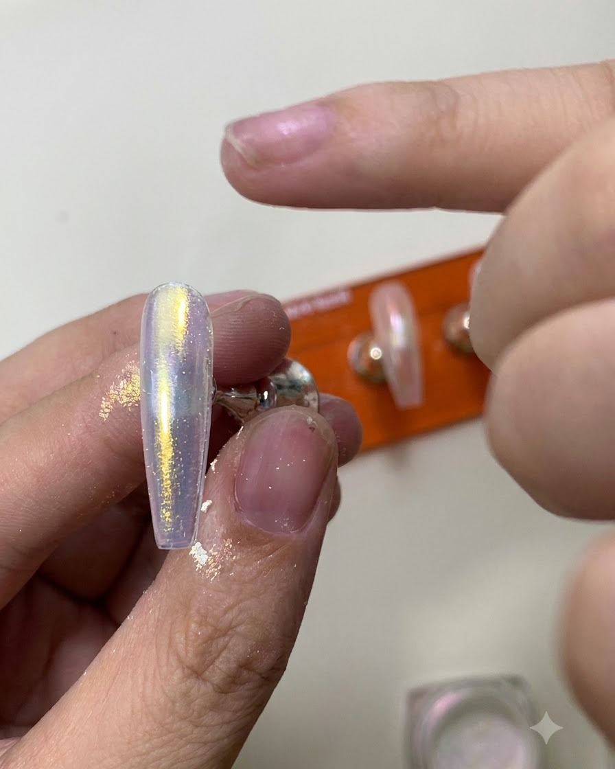 Un outil en silicone frottant de la poudre chrome aurora chatoyante sur une surface dongle brillante.