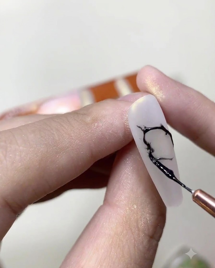 Un pinceau fin mélangeant du vernis gel noir et de la colle à strass transparente sur une palette de maquillage.