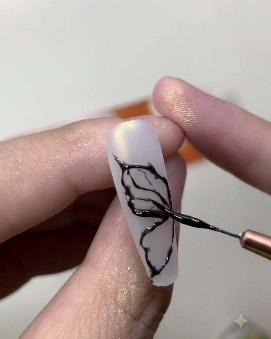 Gros plan dune prothésiste ongulaire utilisant un pinceau fin pour dessiner de délicates lignes dailes de papillon noires sur un ongle blanc laiteux.
