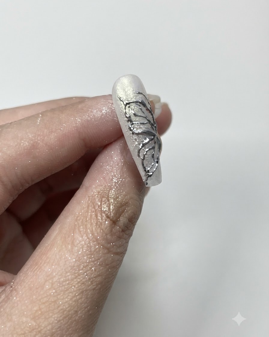 Un pinceau à poussière doux nettoyant lexcédent de poudre chrome argentée sur les bords dun ongle manucuré.