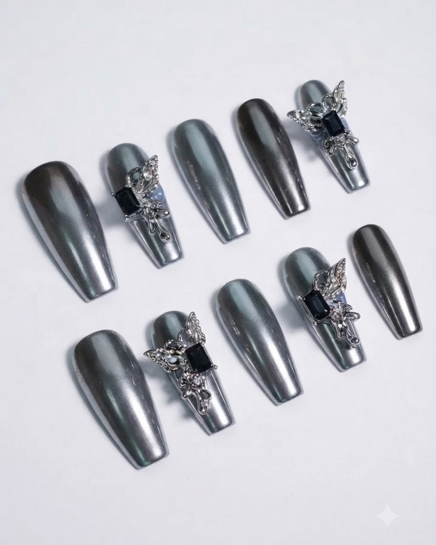 Plan macro détaillé se focalisant sur une pierre précieuse sombre entourée dailes de papillon argentées sculptées sur un ongle chromé.