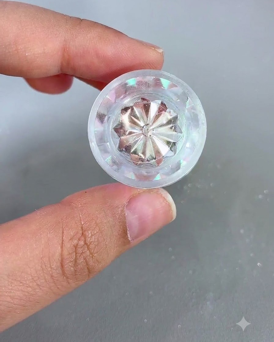 Un pot de poudre chrome iridescente tenu dans une main à côté dun ongle préparé.