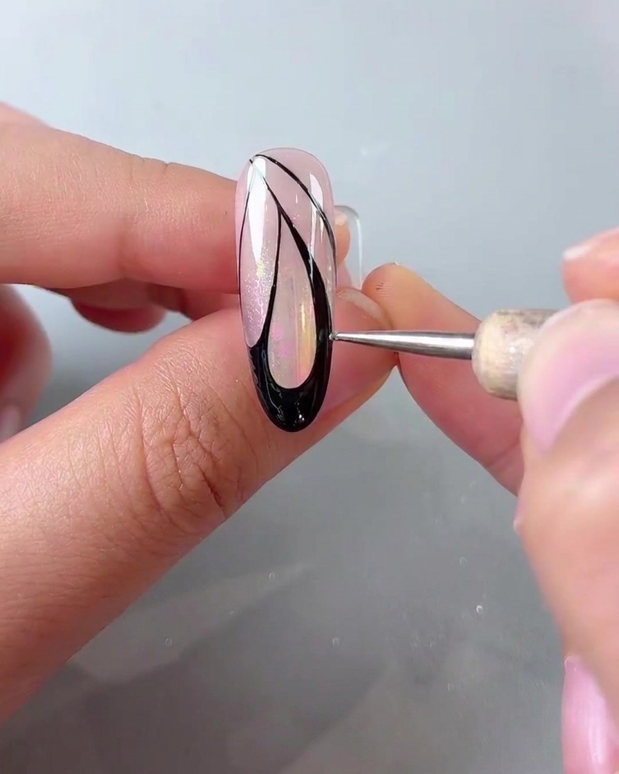 Un stylet de dotting place de petits points blancs le long du bord extérieur du nail art dailes de papillon noires.