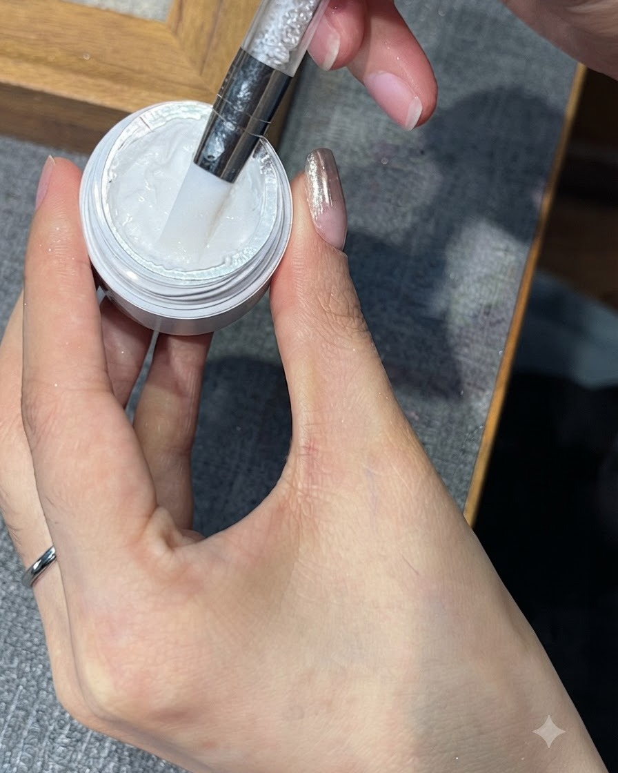 Un outil prélevant une petite quantité de gel de stamping blanc dans son pot.