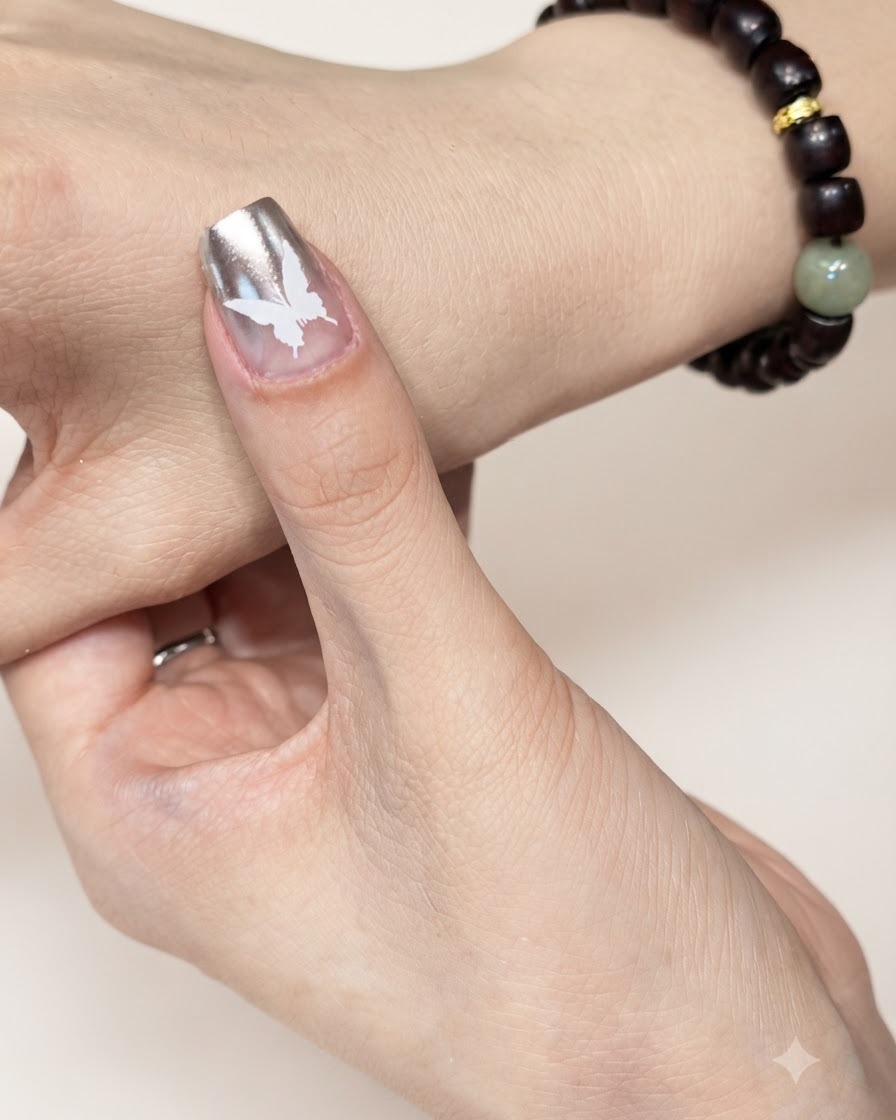 Un ongle manucuré avec un motif de papillon blanc placé sous une lampe de catalysation UV ou LED.